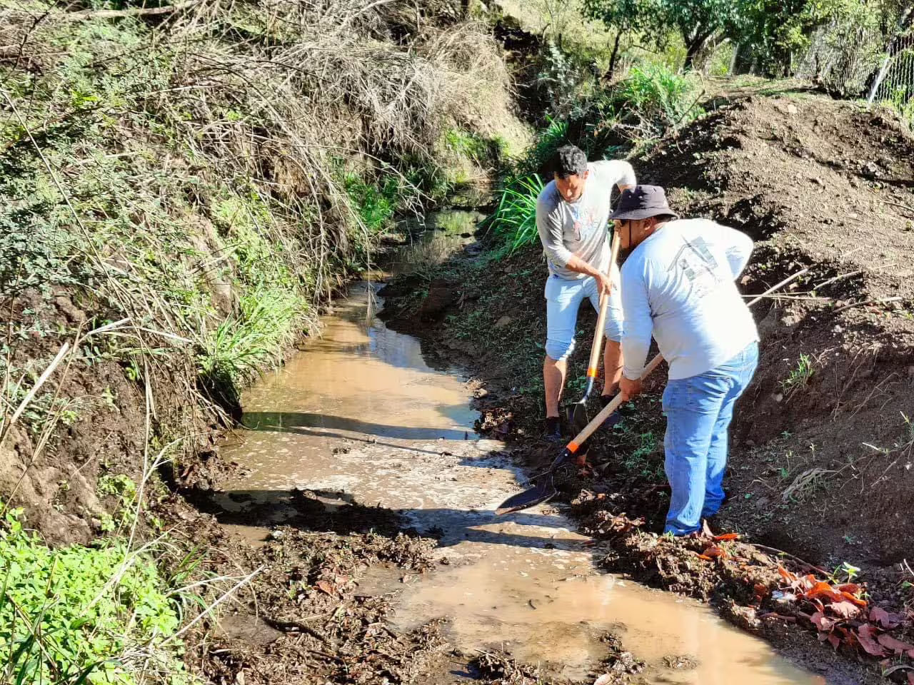 Personas desazolvando el río